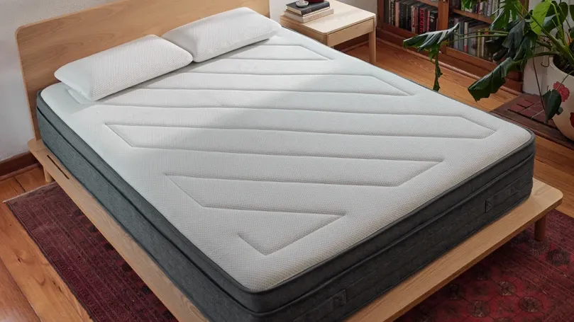 Eva Mattress – Comfort Meets Modern Design Modern bedroom featuring the Eva mattress with a clean white top and grey base, placed on a wooden bed frame.